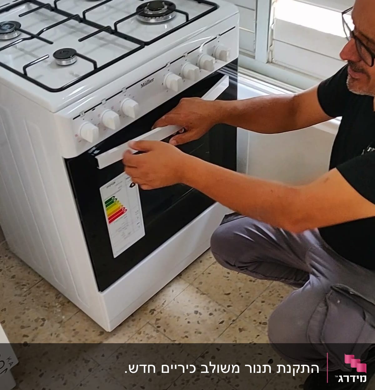 אדם מתקין מדבקה על תנור גז לבן במטבח.